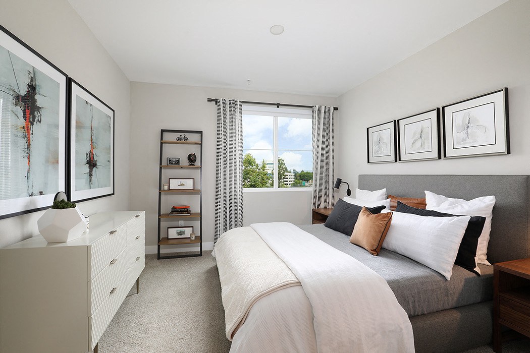Bright bedroom featuring a cozy bed and large window with natural light.